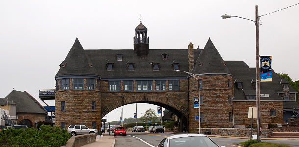 [Huge brick building which spans over the roadway. At each end is a round tower with conical roofs.]